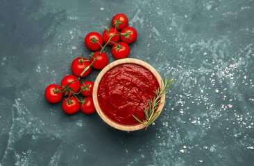 Bowl with tasty tomato paste, rosemary and fresh vegetables on grey grunge background