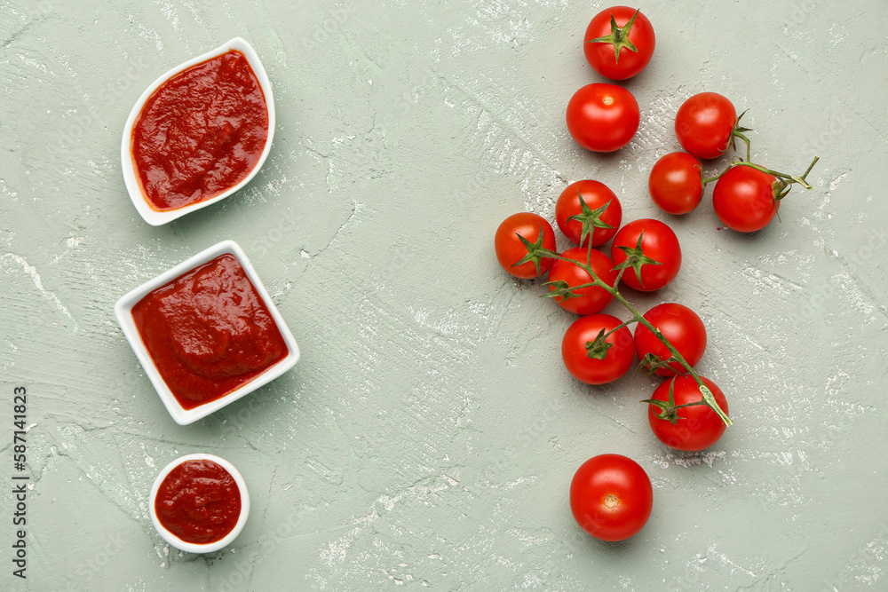 Bowls with tasty tomato paste and fresh vegetables on green grunge background