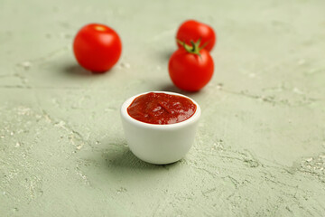 Bowl with tasty tomato paste and fresh vegetables on green grunge background