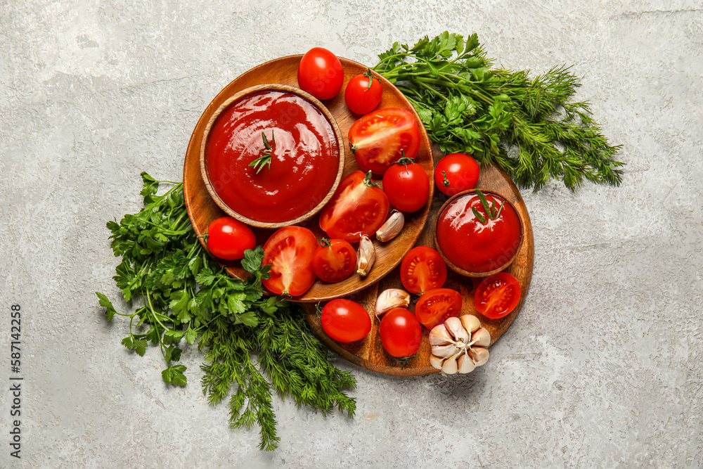 Bowls with tasty ketchup and fresh vegetables on light background