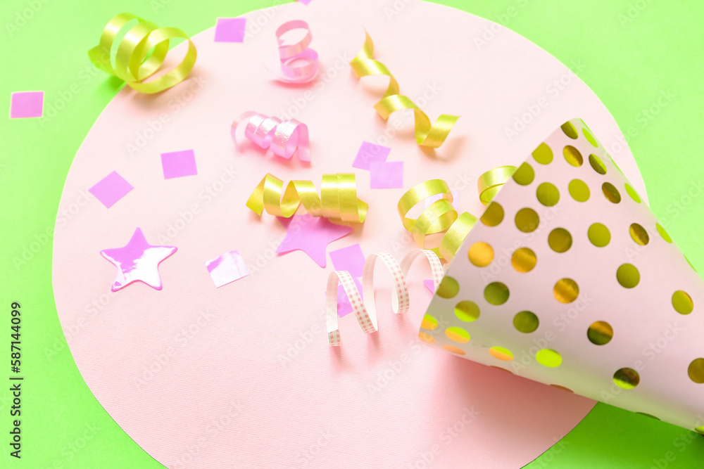 Composition with party hat and confetti on green background