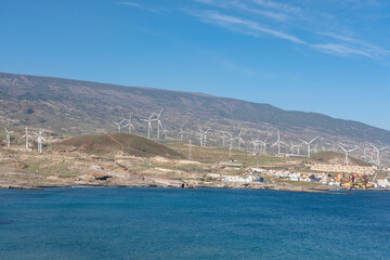 Windmills covering the eastern coast of the island near El Poris de Abona, a small town known for these wind turbines used for generating clean and renewable energy in Tenerife, Canary Islands, Spain