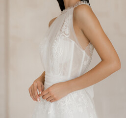 Side view of beautiful brunette bride in long white wedding dress with floral lace. Gorgeous sleeveless wedding dress