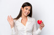 © luismolinero - Young Brazilian woman with an apple isolated on white background saluting with hand with happy expression