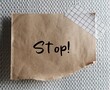 © ariya j - Torn brown paper stick on wall with handwritten word STOP!,concept of thought stopping, to remind self to notice negative thinking and redirect mind to positive one