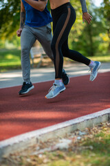 Wall Mural - Legs of boy and girl running on a sports track