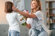 © standret - Happy mother's day, giving flowers. Woman with her little daughter is together in domestic room