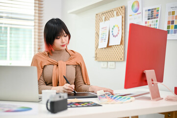 Wall Mural - Attractive Asian female web graphic designer working on her new design project