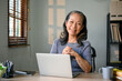 © bongkarn - Successful Asian-aged businesswoman sits at her desk in her modern office.