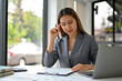 © bongkarn - Focused Asian businesswoman analyzing financial data on reports at her desk.