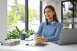 © bongkarn - Attractive young Asian female office worker sits at her office desk.