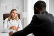A woman doctor receives an African American male patient in her office. Doctor's consultation.
