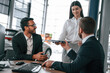 © standret - Woman is giving documents. Three people are working together in the car showroom