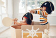 © A. Frank/peopleimages.com - Pirate, box and playing with children in living room for bonding, imagine and creative. Happy, youth and siblings with girls sailing in cardboard ship in family home for relax, fantasy and games