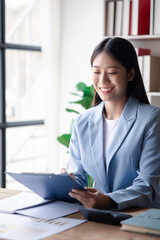 Wall Mural - A businesswoman is checking company financial documents and using a tablet to talk to the chief financial officer through a messaging program. Concept of company financial management.