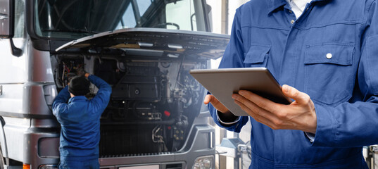 Poster - Serviceman with digital tablet on the background of the truck in the car service