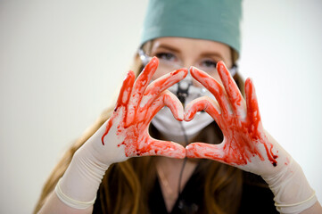 Fototapeta operation and medicine theme bloody hand surgeon holding a human heart in a bloody white gloves isolated on a white background in studio. high quality photo
