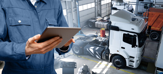 Serviceman with digital tablet on the background of the truck in the car service