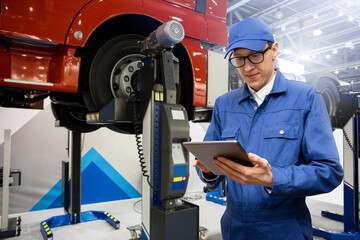 Poster - Serviceman with digital tablet on the background of the truck in the car service