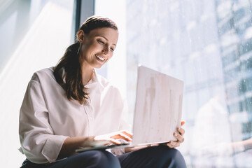 Cheerful female entrepreneur working on laptop