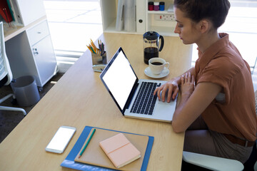 Poster - Female executive using laptop at desk in office