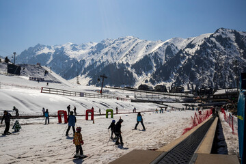 Almaty Kazakhstan 25 March 2023. Medeo Shymbulak Mountain Resort's ski slopee with skiers and snowboarders. Skiers at slopes of ski resort Chimbulak. 