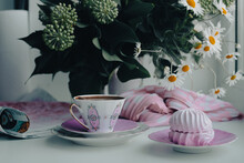 A Gorgeous Fragile White-pink Coffee Cup On A Large Soft Pink Napkin And A Puffy Airy Pink Marshmallow In A Saucer On A White Table. Stylish Pink Dot Scarf And Beautiful Sunny Daisies In White Vase.