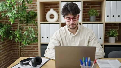 Canvas Print - Young hispanic man business worker using laptop with idea expression at office