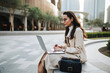 © MVProductions - Young woman with sunglasses sitting in Dubai and doing work on laptop. Student or freelancer lifestyle. High quality generative ai
