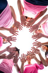 Wall Mural - Directly below shot of females in pink outfits showing hands for breast cancer awareness