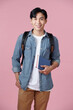 © makistock - Smart guy student with backpack and bunch of books smiling at camera, copy space for advertisement over pink background