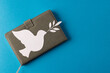 Close up of white dove with leaf over notebook and copy space on blue background