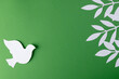 Close up of white dove with leaves and copy space on green background
