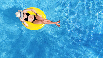 Wall Mural - Beautiful woman in hat in swimming pool aerial drone view from above, young girl in bikini relaxes and swims on inflatable ring donut and has fun in water on tropical vacation on holiday resort
