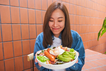 Wall Mural - Portrait image of a young woman holding and eating salad