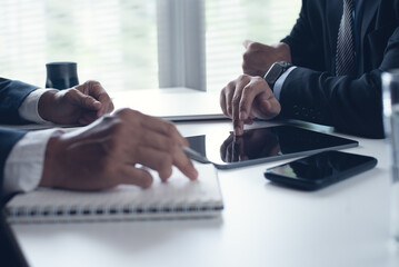 Wall Mural - Two businessmen sitting at table, using digital tablet and laptop co-working at modern office, close up. Business colleagues working together, having a discussion on a project