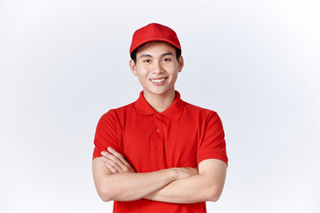 Smiling delivery man in red uniform standing with arm crossed - isolated on white background