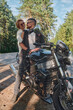© perfectlab - Middle age couple hugging and having fun, sitting on a motorcycle, traveling together on a forest road