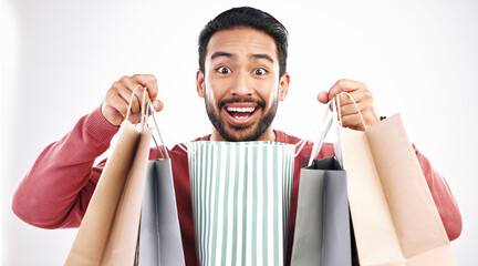 Wall Mural - Wow, sale and portrait of man with shopping bag in studio, excited for discount or purchase on white background. Deal, face and indian guy with product from shop, mall or market while posing isolated