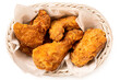 Crispy fried chicken pieces in a white woven basket isolated on white from above.
