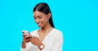 © Nina/peopleimages.com - Phone, typing and young woman isolated on blue background for social media post, networking and chat tech. Happy indian person or online user with mobile app, smartphone or cellphone in studio mockup