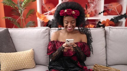 Canvas Print - African american woman wearing katrina costume using smartphone at home