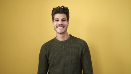 Wall Mural - Young hispanic man smiling confident standing over isolated yellow background