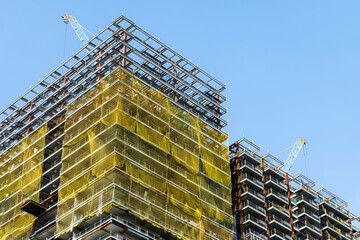 Wall Mural - Cranes and steel structures of building construction with a blue sky background.