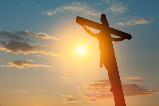 Silhouette of the crucified Jesus Christ on the cross on background of sunset sky.