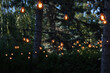 Lamp garland on a tree branch. Backyard illumination, light in the evening garden, electric lanterns with round diffuser. 