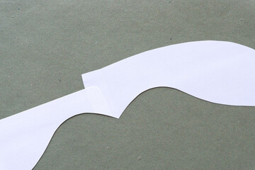 Poster - white cut paper shape with distinct wavy form on rough green paper