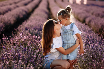 Wall Mural - Happy family in purple lavender field. young beautiful mother and child Girl enjoy walking blooming meadow on summer day. Mom having fun with pretty daughter in nature on sunset. mothers day