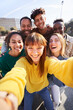 © CarlosBarquero - Vertical photo of a Group of happy friends posing for a selfie on a spring day as they party together outdoors. Group of multicultural friends having a good time together on the weekend.