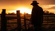 © Caseyjadew - Silhouette image of farmer leaning against fence post thoughtfully at sunset. Time out after a long day's work on the land.